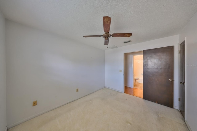 unfurnished bedroom with ceiling fan, light carpet, and a textured ceiling