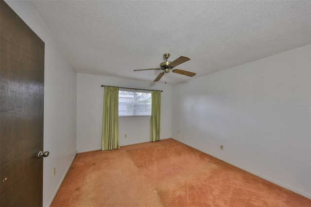 spare room featuring ceiling fan, light colored carpet, and a textured ceiling