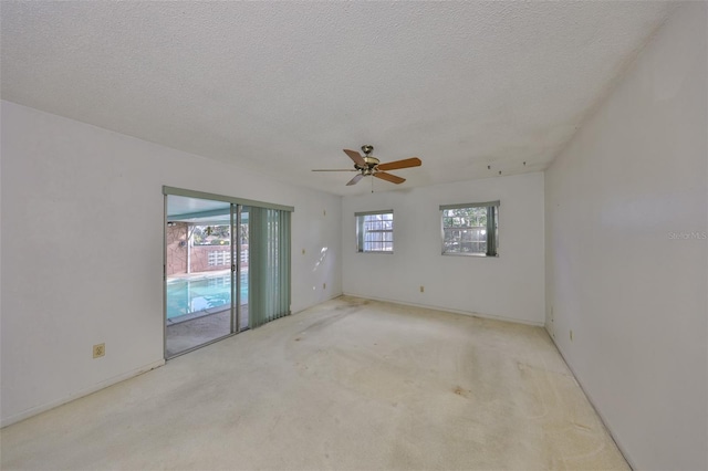 empty room featuring ceiling fan, light carpet, and a textured ceiling