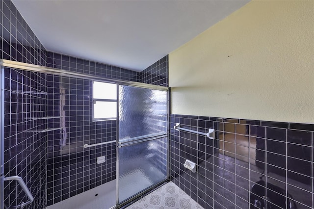 bathroom with a shower with door and tile walls