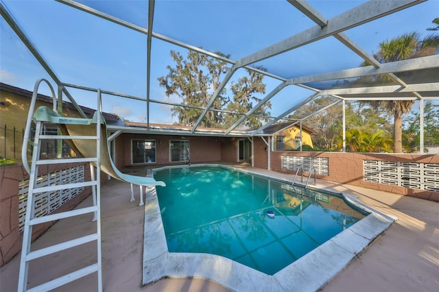 view of pool featuring a patio area, glass enclosure, and a water slide