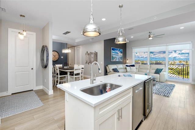 kitchen with sink, white cabinetry, decorative light fixtures, dishwasher, and a kitchen island with sink