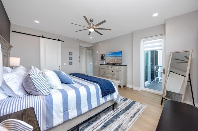 bedroom with ceiling fan, a barn door, and light wood-type flooring