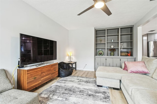 living room with a textured ceiling, light hardwood / wood-style flooring, and ceiling fan