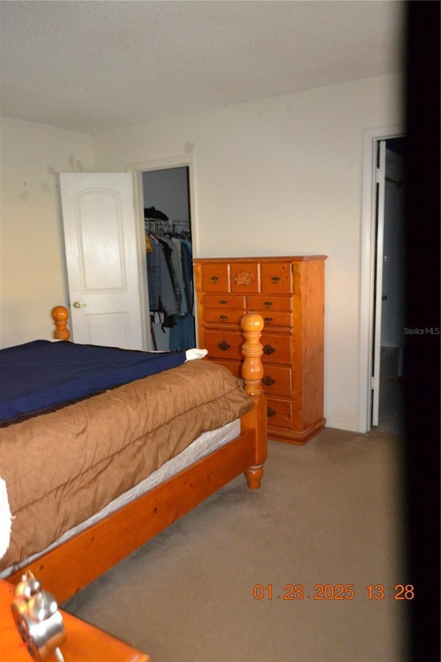 bedroom featuring a walk in closet, light colored carpet, and a closet