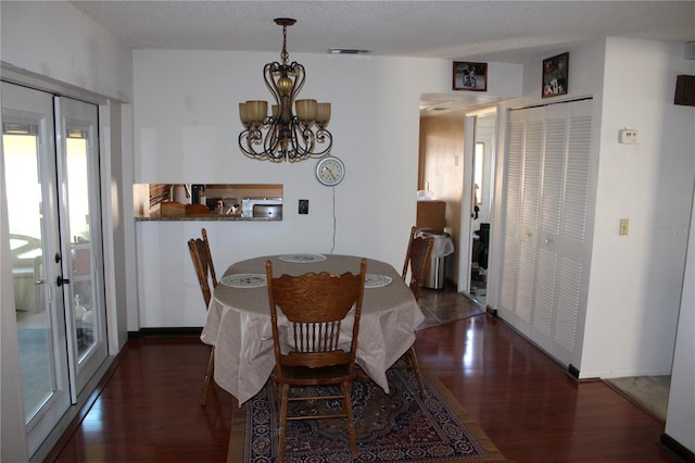 dining area with a notable chandelier, dark wood-type flooring, and a textured ceiling