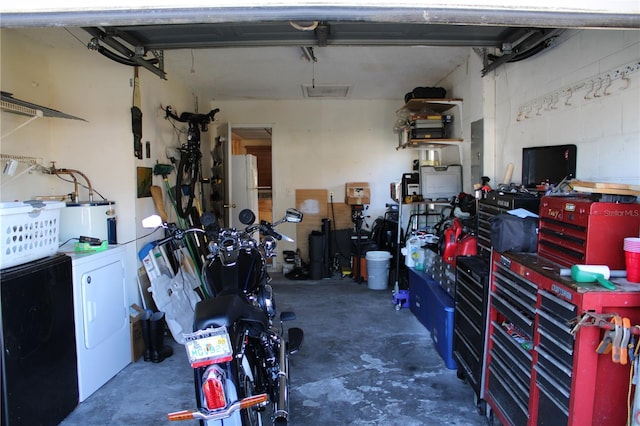 garage with separate washer and dryer, a workshop area, water heater, and white fridge