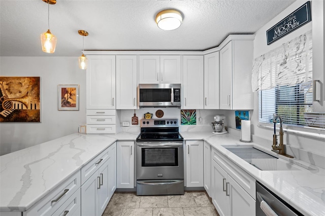 kitchen featuring pendant lighting, sink, appliances with stainless steel finishes, white cabinetry, and light stone counters