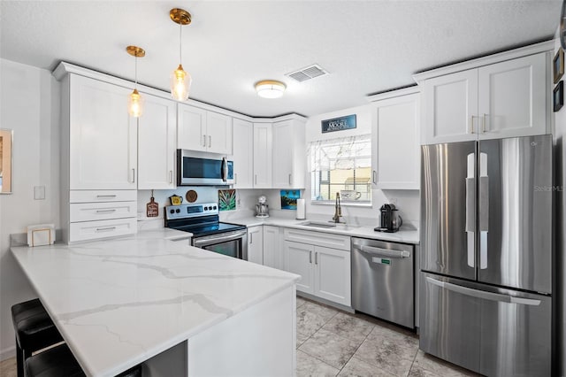 kitchen with pendant lighting, sink, white cabinets, kitchen peninsula, and stainless steel appliances