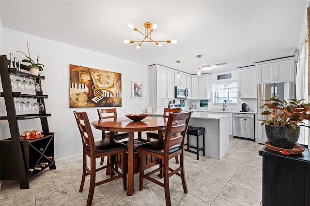 dining space featuring an inviting chandelier, sink, and a textured ceiling