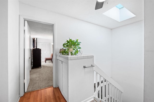 hallway with wood-type flooring, a skylight, and a textured ceiling