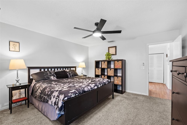 carpeted bedroom featuring ceiling fan and a textured ceiling