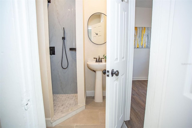 bathroom featuring tile patterned floors, sink, and a tile shower