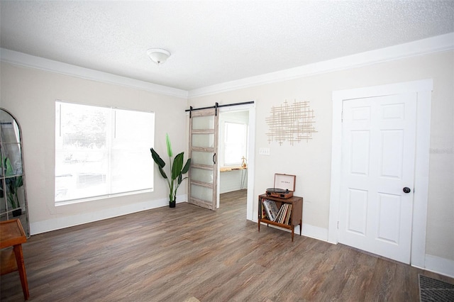 unfurnished room featuring plenty of natural light, a barn door, and dark hardwood / wood-style flooring