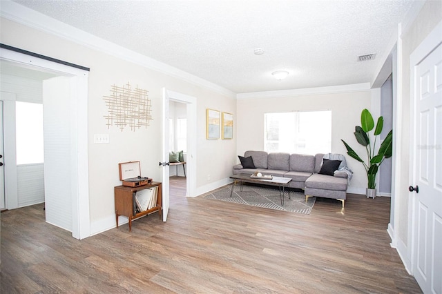 living room featuring crown molding, hardwood / wood-style floors, and a textured ceiling