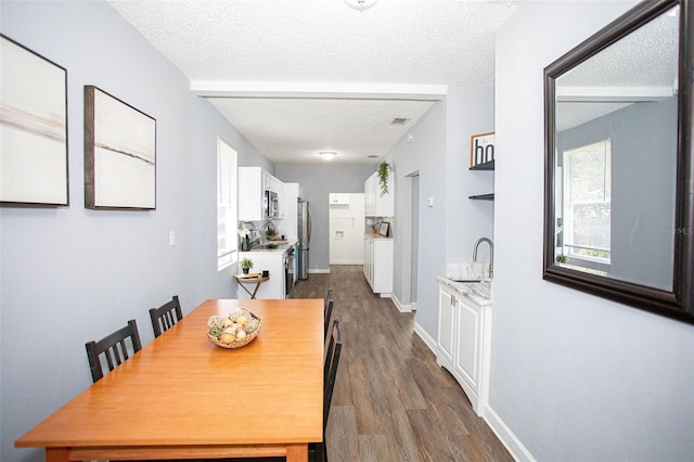 dining space featuring sink, dark wood-type flooring, and a textured ceiling