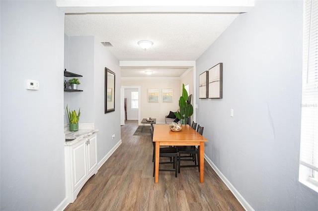 dining room featuring plenty of natural light, dark hardwood / wood-style flooring, and a textured ceiling