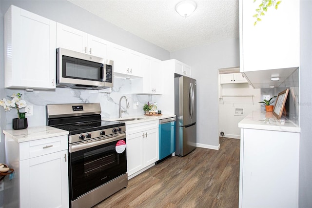 kitchen featuring appliances with stainless steel finishes, dark hardwood / wood-style floors, white cabinetry, sink, and a textured ceiling