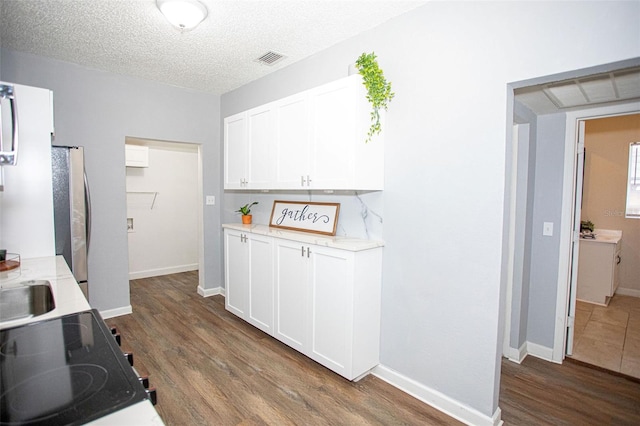 kitchen with white cabinetry, dark hardwood / wood-style floors, stainless steel fridge, and a textured ceiling