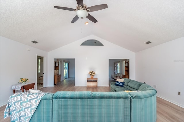 living room with hardwood / wood-style flooring, lofted ceiling, a textured ceiling, and ceiling fan