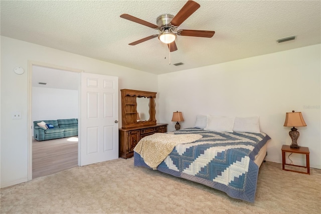 carpeted bedroom with ceiling fan and a textured ceiling