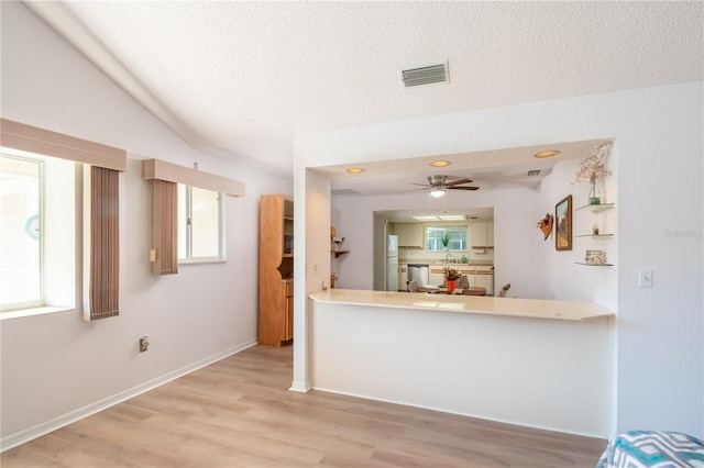 kitchen with dishwasher, light hardwood / wood-style floors, a textured ceiling, and kitchen peninsula