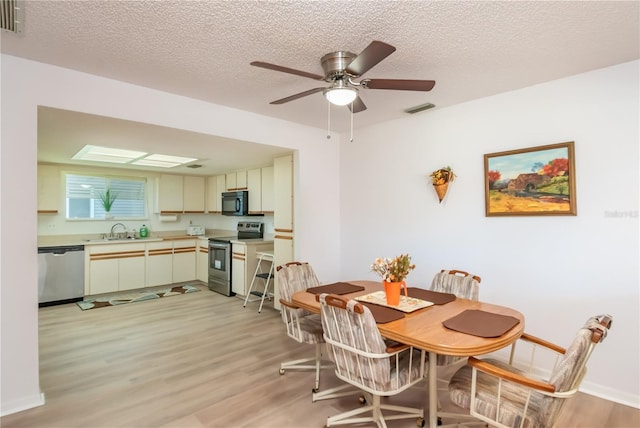 dining space featuring sink, light hardwood / wood-style flooring, and a textured ceiling