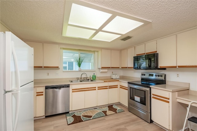 kitchen featuring sink, light hardwood / wood-style flooring, a textured ceiling, and appliances with stainless steel finishes