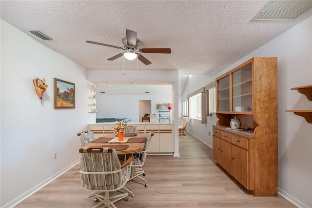 dining room with ceiling fan, light hardwood / wood-style floors, and a textured ceiling