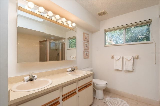 bathroom featuring vanity, a textured ceiling, a shower with shower door, tile patterned floors, and toilet