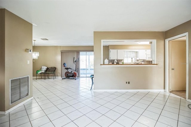 unfurnished living room featuring an inviting chandelier and light tile patterned floors