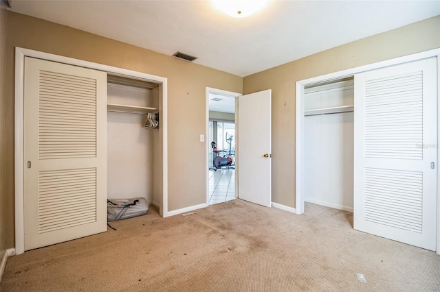 unfurnished bedroom with light carpet and two closets