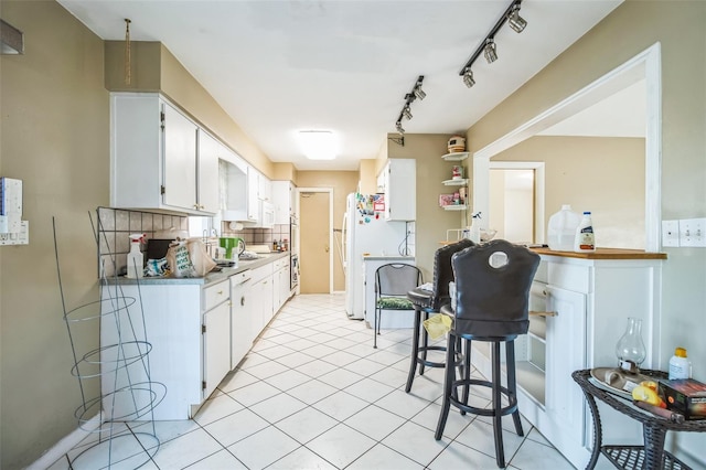 kitchen featuring white cabinetry, track lighting, light tile patterned floors, and backsplash