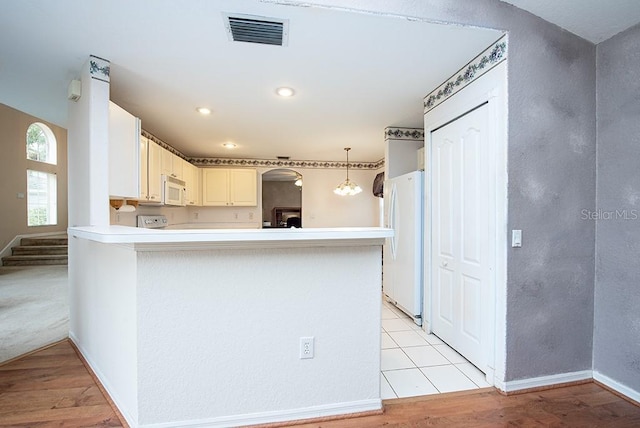 kitchen featuring pendant lighting, white appliances, white cabinetry, kitchen peninsula, and light wood-type flooring