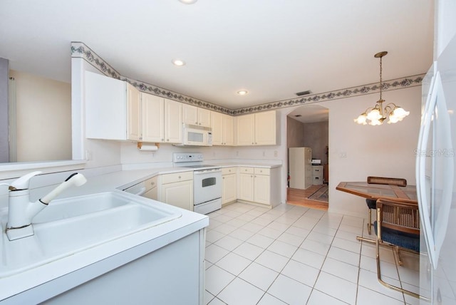 kitchen featuring sink, white appliances, light tile patterned floors, hanging light fixtures, and white cabinets