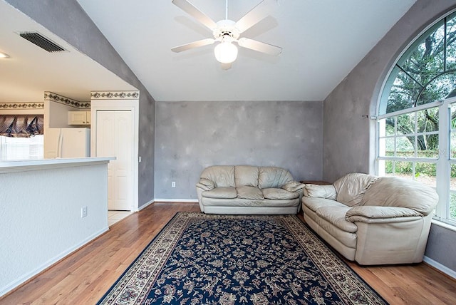 living room featuring ceiling fan, vaulted ceiling, and light hardwood / wood-style flooring