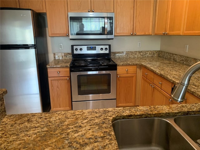 kitchen featuring appliances with stainless steel finishes, sink, and stone countertops