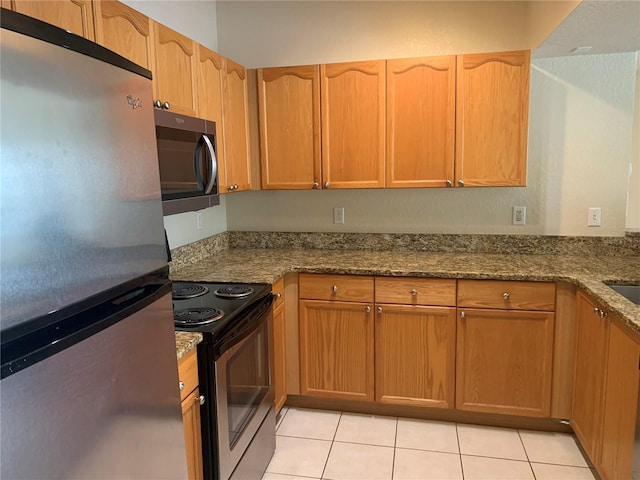 kitchen featuring appliances with stainless steel finishes, stone countertops, and light tile patterned floors