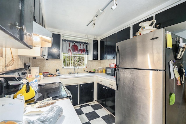 kitchen featuring sink, track lighting, electric range oven, and stainless steel refrigerator