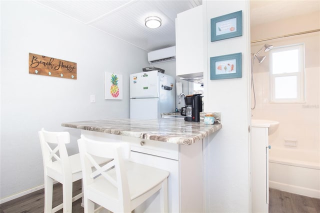 kitchen featuring sink, white cabinetry, an AC wall unit, white refrigerator, and dark hardwood / wood-style flooring