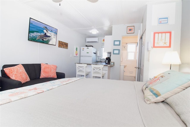 bedroom featuring white refrigerator, ensuite bathroom, sink, and an AC wall unit