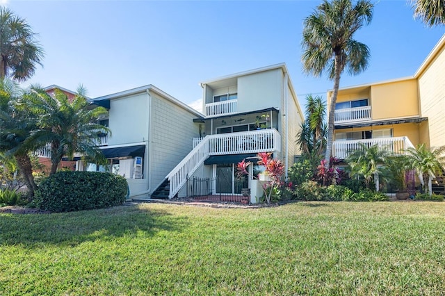 rear view of house featuring a yard and a balcony