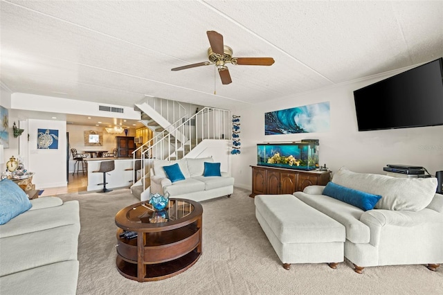 living room with ceiling fan, light colored carpet, and a textured ceiling