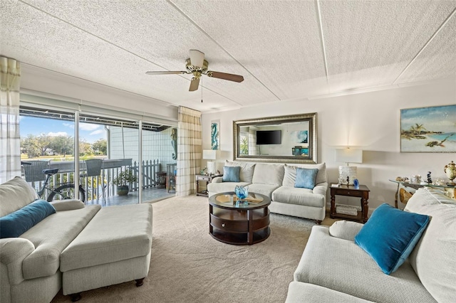 carpeted living room featuring ceiling fan and a textured ceiling