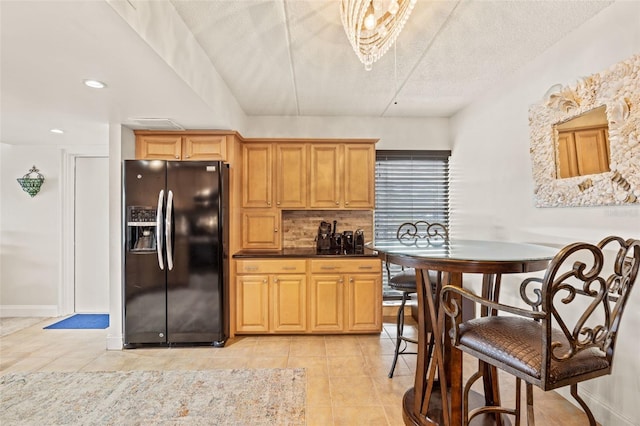 kitchen featuring tasteful backsplash, light tile patterned flooring, light brown cabinetry, and black refrigerator with ice dispenser