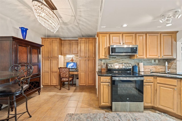 kitchen with light tile patterned flooring, appliances with stainless steel finishes, a notable chandelier, dark stone counters, and backsplash