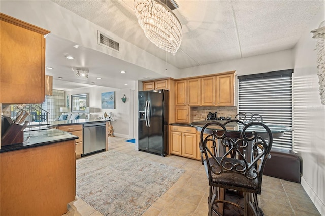 kitchen with tasteful backsplash, black fridge, stainless steel dishwasher, kitchen peninsula, and a chandelier