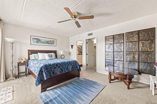 bedroom with carpet floors, a textured ceiling, ceiling fan, and ensuite bath