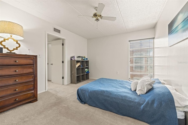 carpeted bedroom featuring ceiling fan and a textured ceiling