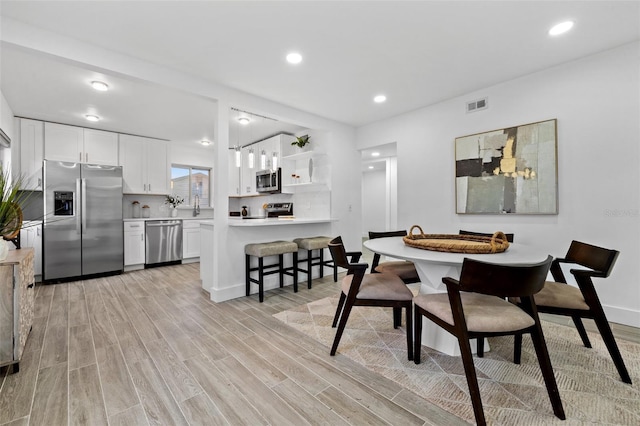 dining space with light wood-style flooring, visible vents, and recessed lighting